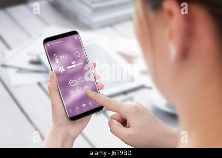 Donna utilizzare smart home control app sul telefono cellulare. Foto Stock