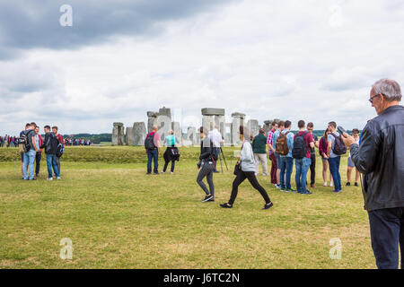 La folla di turisti a Stonehenge, uomo l'ascolto di audio su questo sito storico Foto Stock