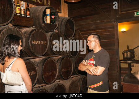 Guida di fronte di barili in Havana Club famosa distilleria di rum e museo explans il processo di attrattiva turistica femmina. Foto Stock