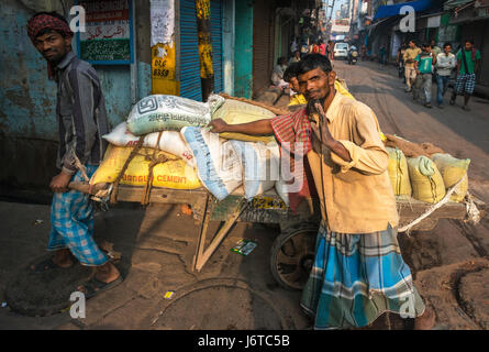 Delhi, India - 10 novembre 2012 - tre uomini spingendo un carrello con materiale constuction, che illustra il fatto che il lavoro manuale è ancora una forma dominante di lavoro Foto Stock