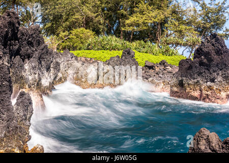 Un vibrante, scenic Hawaiian cove con lavaggio onde shore evidenzia il clima tropicale e cercare di paradiso. Foto Stock