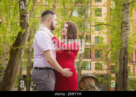 Felice coppia giovane aspetta baby in estate park Foto Stock