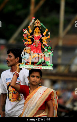 Un devoto Hiindu trasporta l'idolo della dea Durga a Bina Smriti Ghat vicino a Dhaka's Sadarghat per l'immersione. Dacca in Bangladesh. Foto Stock