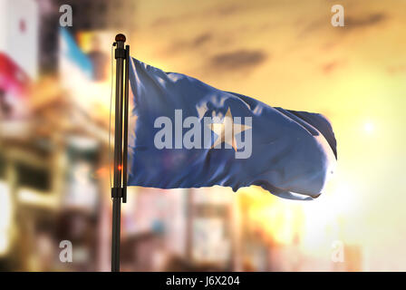 Somalia bandiera contro città sfondo sfocato di Sunrise retroilluminazione Foto Stock