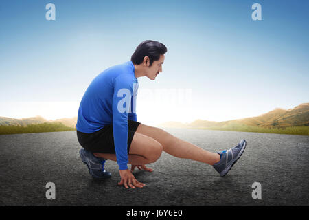 Giovani asiatici runner stretching le gambe dopo la esecuzione di esercizio all'aperto Foto Stock