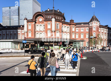 TOKYO - 4 Maggio 2017: pedoni che attraversano la strada verso la Tokyo train station, la cui architettura è in contrasto con gli edifici nel dis aziendali Foto Stock