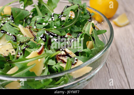 La rucola (razzo) insalata condita con aceto balsamico salsa di soia , scaglie di parmigiano e pepe nero macinato fresco, di sesamo. Inquadratura orizzontale. Foto Stock