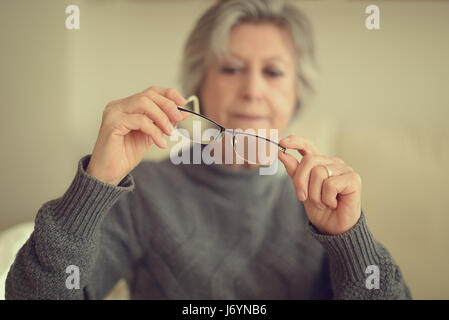 Senior donna mettendo sul suo bicchieri Foto Stock