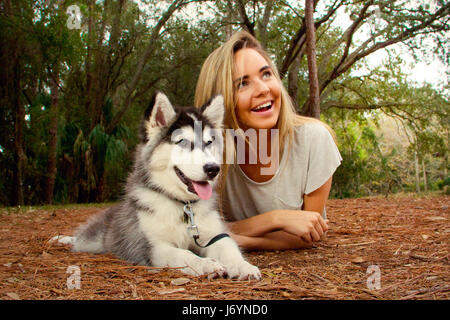Donna che giace a terra con il cane cucciolo di Husky siberiano, San Pietroburgo, Florida, Stati Uniti
