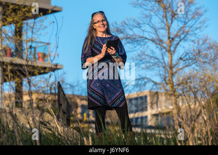 Donna in piedi nel giardino della messaggistica di testo Foto Stock