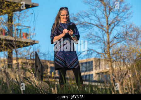 Donna in piedi nel giardino della messaggistica di testo Foto Stock