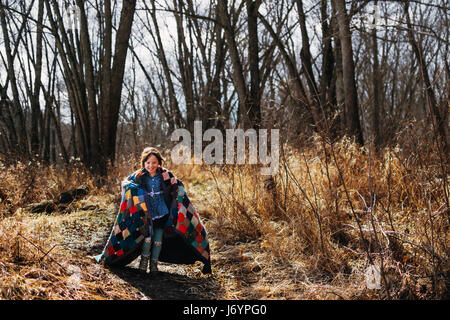 Ragazza che corre attraverso la foresta avvolto in una coperta Foto Stock