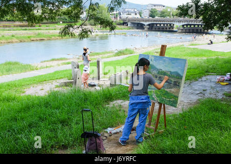 Una donna di dipingere un quadro dal fiume Kamogawa in Kyoto, Giappone. Foto Stock