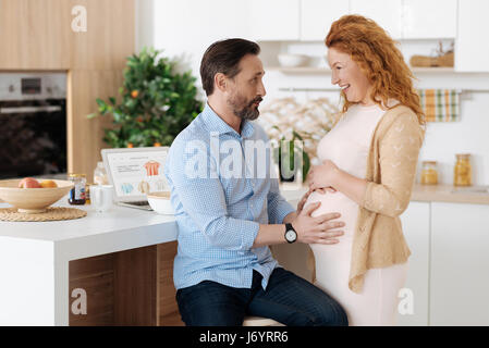 Dolce futuro padre e la mamma chiacchierando in cucina Foto Stock