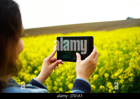 Una giovane donna fare foto in canola field Foto Stock
