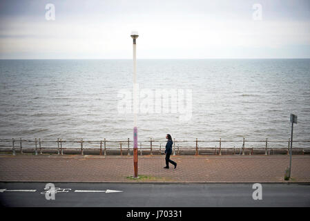 Lone figura passeggiando lungo la Promenade di Blackpool con alta marea Foto Stock