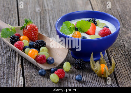 Yogurt bianco con un misto di frutta fresca in un blu vaso in ceramica Foto Stock