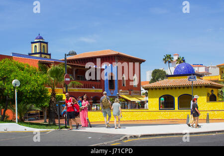 Turisti visitano il centro commerciale locale con la sua architettura distintivo su una calda giornata di sole in Playa Las Americas in Teneriffe Foto Stock