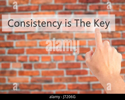 La coerenza è la chiave - Mano premendo un pulsante sul fondo sfocato concetto . Business, tecnologia internet concetto. Stock Photo Foto Stock