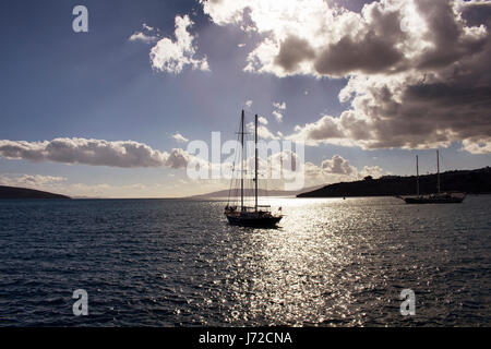 Sun luce irrompe attraverso le nuvole in cielo drammatico. Essa brilla sulla superficie del mare a Bodrum Turchia sudoccidentale. La luce di retromarcia rendono yachts e guardare il paesaggio Foto Stock