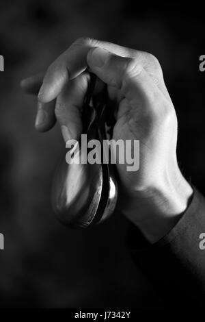 Primo piano della mano di un giovane uomo caucasico giocando le nacchere contro uno sfondo scuro, in bianco e nero Foto Stock