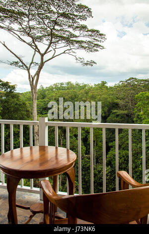 Sedia in legno e tavolo per 1 persona in un balcone che si affaccia su una foresta appena fuori Kandy, Sri Lanka. Foto Stock