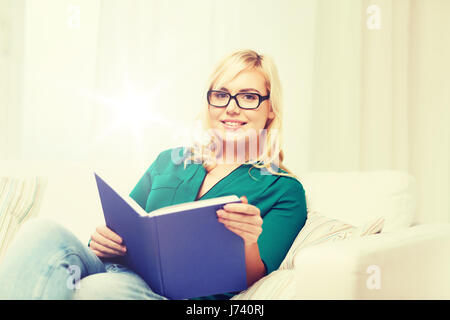 Giovane donna in bicchieri libro di lettura a casa Foto Stock