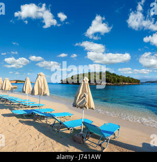 Mattinata estiva Ksamil sabbiosa spiaggia con lettini e ombrelloni (Albania). Due colpi stitch immagine ad alta risoluzione. Foto Stock