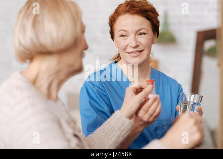 Infermiere diligente assicurandosi che il suo paziente la somministrazione dei farmaci Foto Stock