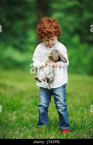 Little Boy con coniglio sull'erba Foto Stock