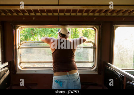 Un uomo che guarda fuori una finestra del treno a Cuba. Foto Stock