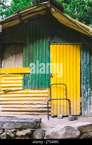 Un capannone o shack fatta di ferro ondulato verniciato di verde e giallo trovato nella campagna fuori Ella e Nuwara Eliya, Sri Lanka. Foto Stock