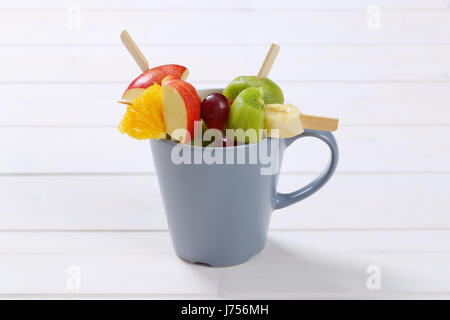 Coppa di frutta fresca spiedini di bianco su sfondo di legno Foto Stock