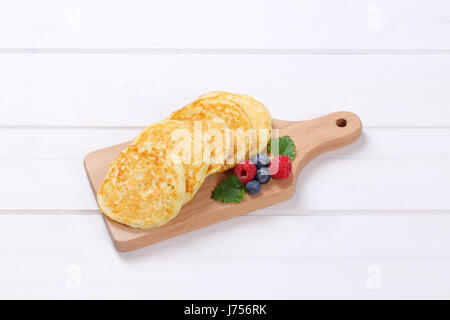 Fresco frittelle americane con lamponi e mirtilli sul tagliere di legno Foto Stock