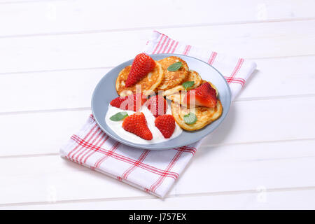 Piastra della american pancake con yogurt bianco e fragole fresche su asciugamano a scacchi Foto Stock