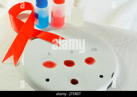 Il prelievo di campioni di sangue e di analisi in un laboratorio di biochimica su uno sfondo luminoso con un nastro rosso. Foto Stock