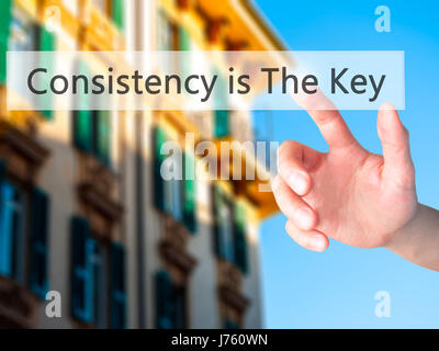 La coerenza è la chiave - Mano premendo un pulsante sul fondo sfocato concetto . Business, tecnologia internet concetto. Stock Photo Foto Stock