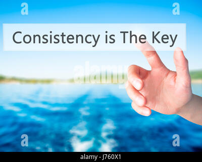 La coerenza è la chiave - Mano premendo un pulsante sul fondo sfocato concetto . Business, tecnologia internet concetto. Stock Photo Foto Stock