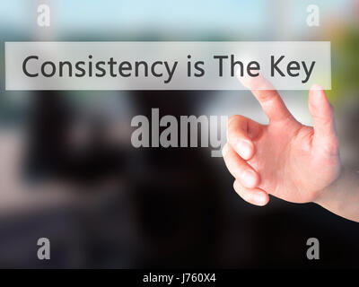 La coerenza è la chiave - Mano premendo un pulsante sul fondo sfocato concetto . Business, tecnologia internet concetto. Stock Photo Foto Stock