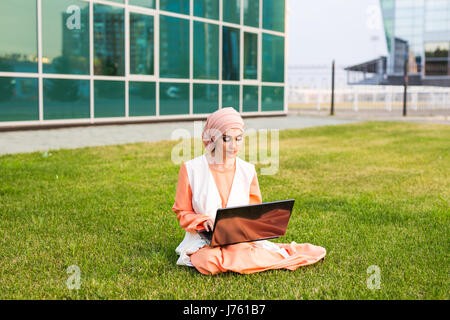 Una giovane donna musulmana utilizzando laptop all'aperto Foto Stock