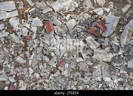 Migliaia di piccole schegge di un vecchio piastrella e intonaco sulla terra foresta come sfondo Foto Stock