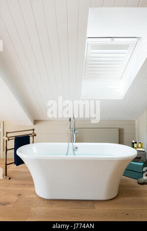 Free standing bath in piano superiore camera da letto padronale con soffitto spiovente e persiane. Foto Stock