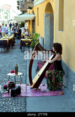 Una giovane donna suonare l'arpa busks in Navigli a Milano Italia Foto Stock