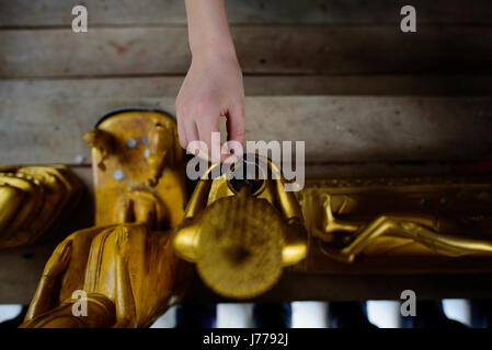 Ritagliate la mano del ragazzo mettendo coin in scultura Foto Stock