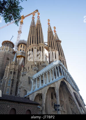 Elaborate guglie scolpite e la costruzione di gru e la facciata della Passione di Gaudi Sagrada Familia Basilica, Barcelona, Spagna. Foto Stock