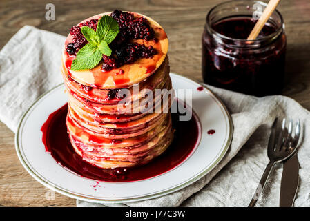 Pila di casalinga frittelle americane con la marmellata di fragole e su sfondo di legno. Foto Stock