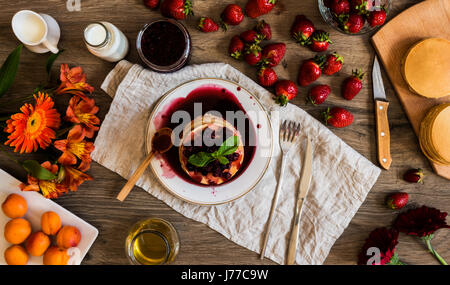 Vista superiore della pila in casa american pancake con la marmellata di fragole e su sfondo di legno. Foto Stock