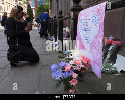 Manchester, Regno Unito. 23 Maggio, 2017. Persone in lutto delle preghiere e dei laici a omaggi floreali per i morti al di fuori di San rna chiesa nel centro della città di Manchester, il giorno dopo un attentato suicida ha ucciso 22 come folle sono state lasciando il Ariana Grande concerto presso l'Arena di Manchester. Credito: Chris Rogers/Alamy Live News Foto Stock