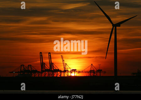 Tilbury, Essex, Regno Unito. 23 Maggio, 2017. Il sole visto impostazione dietro la gru di banchina e delle turbine a vento di Tilbury Docks attraverso il Fiume Tamigi a Gravesend la sera del 23 maggio. Rob Powell/Alamy Live News Foto Stock