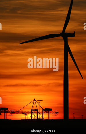 Tilbury, Essex, Regno Unito. 23 Maggio, 2017. Il sole visto impostazione dietro la gru di banchina e delle turbine a vento di Tilbury Docks attraverso il Fiume Tamigi a Gravesend la sera del 23 maggio. Rob Powell/Alamy Live News Foto Stock